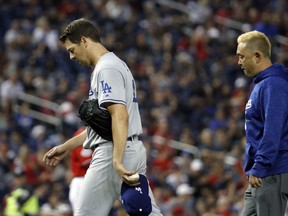 Los Angeles Dodgers starting pitcher Rich Hill, left, walks off the field after throwing two pitches during the first inning of the second baseball game of a doubleheader against the Washington Nationals at Nationals Park, Saturday, May 19, 2018, in Washington.