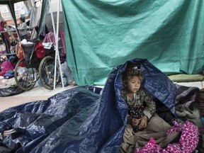 A girl who traveled with a caravan of Central American migrants awakens where the group set up camp to wait for access to request asylum in the U.S., outside the El Chaparral port of entry building at the U.S.-Mexico border in Tijuana, Mexico, Tuesday, May 1, 2018.