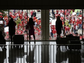 People watch from inside the Legislative Building as participants gather during a teachers rally at the General Assembly in Raleigh, N.C., Wednesday, May 16, 2018. Thousands of teachers rallied the state capital seeking a political showdown over wages and funding for public school classrooms.