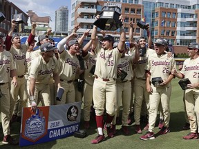 Florida State's Cal Raleigh (35) lifts the trophy following an Atlantic Coast Conference NCAA college baseball tournament championship game against Louisville in Durham, N.C., Sunday, May 27, 2018. Florida State won 11-8.