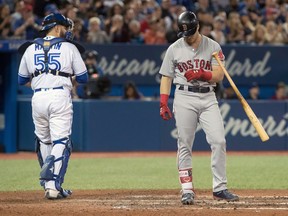 FILE - In this April 24, 2018, file photo, Boston Red Sox's Andrew Benintendi strikes out during the eighth inning for his fourth strikeout of the night, as Toronto Blue Jays catcher Russell Martin walks away during a baseball game in Toronto. There were more strikeouts than hits in the first month of the season, when home runs dipped from last year's record during a cold and wet April.
