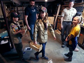 FILE - In this March 1, 2018, file photo, Tatum Weir, center, carries a tool box she built as her twin brother Ian, left, follows after a Cub Scout meeting in Madbury, N.H. Fifteen communities in New Hampshire are part of an "early adopter" program to allow girls to become Cub Scouts and eventually Boy Scouts. For 108 years, the Boy Scouts of America's flagship program for older boys has been known simply as the Boy Scouts. With girls soon entering the ranks, the BSA says that iconic name will change to "Scouts BSA." The change will take effect in February 2019.