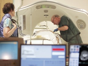 FILE - In this June 3, 2010, file photo, Dr. Steven Birnbaum works with a patient in a CT scanner at Southern New Hampshire Medical Center in Nashua, N.H. According to a study released on Wednesday, May 16, 2018, less than 2 percent of eligible current and former smokers have sought free lung cancer screening, five years after government and private insurers started paying for it.