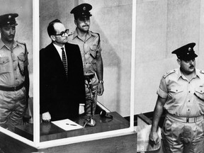 FILE - The 1961 file photo shows Adolf Eichmann standing in his glass cage, flanked by guards, in the Jerusalem courtroom during his trial in 1961 for war crimes committed during World War II. A seven-man Mossad team seized Eichmann in Buenos Aires and brought him to Israel for trial. The Mossad, long shrouded in mystery and mythology, is legendary in international intelligence circles for being behind what are believed to be some of the most daring covert operations of the past century. (AP Photo/File)