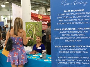 FILE- In this Jan. 31, 2018, file photo, a woman speaks to Maui Divers Jewelry representatives at a job fair in Honolulu. On Wednesday, May 2, payroll processor ADP reports how many jobs private employers added in April.