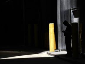FILE- In this June 6, 2017, file photo, a man checks his phone in an alley in downtown Chicago. A security researcher says a website flaw at a U.S. company could have allowed anyone to pinpoint the location of nearly any cellphone in the United States. The lapse at LocationSmart, a company that gathers real-time data on cellular wireless devices, is the latest to highlight how little protection consumers have from trafficking in data about their location.