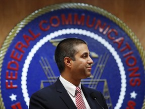 FILE - In this Dec. 14, 2017, file photo, after a meeting voting to end net neutrality, Federal Communications Commission (FCC) Chairman Ajit Pai smiles while listening to a question from a reporter in Washington. The FCC has set June 11 as the repeal date for "net neutrality" rules meant to prevent broadband companies from exercising more control over what people watch and see on the internet. Pai says the repeal aims to replace "heavy-handed" rules with a "light-touch" approach to Internet regulation.