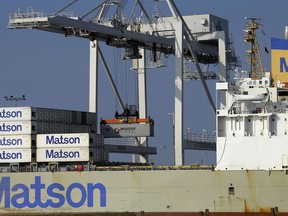 FILE - In this Dec. 13, 2017 file photo, a container ship is unloaded at the Port of Oakland in Oakland, Calif.  Record exports trimmed the U.S. trade deficit in March 2018, the first drop in seven months in a massive gap that President Donald Trump is determined to shrink with an aggressive America First policy.