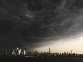 In this Tuesday, May 15, 2018 photo, storm clouds gather over New York city seen from the Hudson River. A line of strong storms pushed across New York City and badly disrupted the evening commute, stranding thousands of train riders.