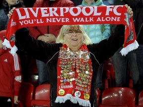 FILE - In this Nov. 1, 2017 file photo, a Liverpool fan holds up a scarf that reads "You'll never walk alone," during the Champions League Group E soccer match between Liverpool and Maribor at Anfield, Liverpool, England. The famous tune will be sung Saturday by 16,000-plus Liverpool fans at Olympic Stadium in Kiev, Ukraine.