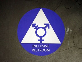 FILE - In this May 17, 2016, file photo, a new sticker designates a gender neutral bathroom at Nathan Hale high school in Seattle. On college campuses and in workplaces, across social media and in deference to nonbinary people, gender-neutral pronouns are more than just a new wave of political correctness.  Pronouns "they" and "them" seem to be winning the race of acceptance as gender neutrals.