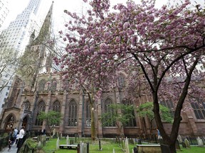 In this May 2, 2018, photo, people walk outside the historic Trinity Church, through churchyard and cemetery in New York. New York City's Trinity Church, a tourist attraction loved for its ties to colonial America and links to a Broadway hit, will be largely closed to visitors during a two-year renovation intended to brighten the church and improve disabled access.