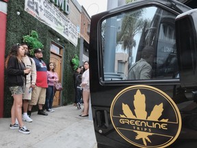 In this May 19, 2018 photo tourists line up before boarding the Green Line Trips bus in the Hollywood section of Los Angeles. Recreational marijuana sales became legal in California this year, and the industry is targeting tourists as well as locals, with tours, shops, lodging and ads. And there are cannabis bus tours, too, like Green Line Trips, with stops at local pot dispensaries and Griffith Park or Santa Monica.