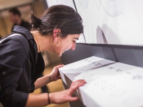 This April 12, 2018 photo provided by the Cooper Hewitt, Smithsonian Design Museum, shows a visitor interacting with the "Smellmap: Amsterdam," by Kate McLean, currently on view in the exhibit "The Senses: Design Beyond Vision" at Cooper Hewitt, Smithsonian Design Museum in New York.