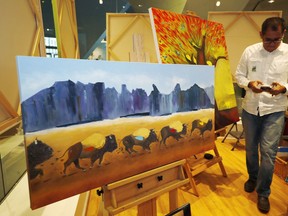 In this Nov. 10, 2017 photo, artist Arturo Garcia walks about his painting of the American bison as the painter takes a break from creating other works as part of an exhibition at the art museum in Denver.