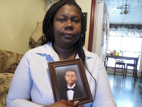 FILE - This April 5, 2018 file photo shows Jameillah Smiley holding a framed photograph of her son, Ricky Boyd, at her home in Savannah, Ga. Police were justified in fatally shooting Ricky Boyd, a 20-year-old man, a grand jury said Wednesday, May 23, 2018 after concluding that he pointed a BB pistol at officers who had come to arrest him.