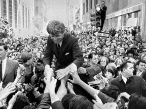 FILE - In this April 2, 1968 file photo U.S. Sen. Robert F. Kennedy, D-NY, shakes hands with people in a crowd while campaigning for the Democratic party's presidential nomination on a street corner, in Philadelphia. Friends and family of U.S. Sen. Robert F. Kennedy will host a memorial service at Arlington National Cemetery on June 6, 2018, to honor him on the 50th anniversary of his assassination.