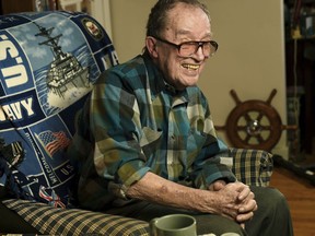 FILE - In this November 2014 file photo, Lawrence J. Reilly Sr., a U.S. Navy veteran of World War ll and the Vietnam War, sits in the living room of his home in Syracuse, N.Y. Reilly, a U.S. Navy veteran who survived the 1969 ship collision that claimed the life of his son and later fought unsuccessfully to have the victims' names inscribed on the Vietnam Veterans Memorial has died. Retired Master Chief Lawrence Reilly Sr.'s daughter says he died Wednesday, May 23, 2018, at a Syracuse hospital from complications from pneumonia. He was 93.