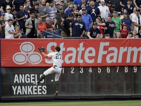 New York Yankees left fielder Giancarlo Stanton (27) prepares to hit the wall while fielding a double from Los Angeles Angels' Mike Trout during the first inning of a baseball game Saturday, May 26, 2018, in New York.