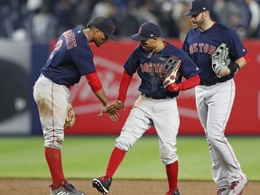 Boston Red Sox shortstop Xander Bogaerts, left, center fielder Mookie Betts, center, and right fielder J.D. Martinez celebrate after the Red Sox defeated the New York Yankees 5-4 in a baseball game in New York, Thursday, May 10, 2018.