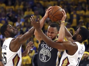 Golden State Warriors' Stephen Curry (30) keeps the ball from New Orleans Pelicans' E'Twaun Moore, left, and Darius Miller during the second half in Game 2 of a second-round NBA basketball playoff series Tuesday, May 1, 2018, in Oakland, Calif.