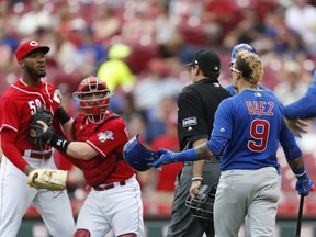 Chicago Cubs' Javier Baez (9) has a few words for Cincinnati Reds relief pitcher Amir Garrett, far left, after striking out during the seventh inning in the first baseball game of a doubleheader, Saturday, May 19, 2018, in Cincinnati.