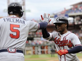 Atlanta Braves' Ozzie Albies, right, celebrates with Freddie Freeman after he scores on a solo home run in the first inning of a baseball game against the Philadelphia Phillies, Sunday, April 29, 2018, in Philadelphia.
