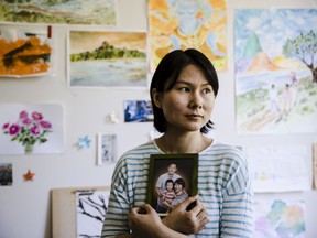 Hua Qu, the wife of Chinese-American Xiyue Wang, poses for a photograph with a portrait of her family in Princeton, N.J., Wednesday, May 9, 2018. Families of several Americans currently detained in Iran are hoping President Donald Trump's decision announced on Tuesday to withdraw from the Iran nuclear deal will not make it harder to get their love ones freed.
