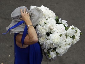 A woman holds onto her hat as she walks on the grounds at the Devon Horse Show and Country Fair, Wednesday, May 30, 2018, in Devon, Pa. First held in 1896, the 11-day event is known for being one of the last old-fashioned horse shows in the nation.