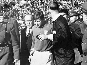 FILE - In this June 2, 1962 file photo, Italian forward Giorgio Ferrini, centre, is sent off by British referee Ken Aston after an incident during the first half of the Football World Cup soccer match against Chile in Santiago. Ferrini refused to leave the field and was removed by police officers. The match has been labelled the Battle of Santiago. The 21st World Cup begins on Thursday, June 14, 2018, when host Russia takes on Saudi Arabia. (AP Photo/File)