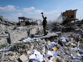 FILE - In this Saturday, April 14, 2018 file photo, a Syrian soldier films the damage of the Syrian Scientific Research Center which was attacked by U.S., British and French military strikes to punish President Bashar Assad for suspected chemical attack against civilians, in Barzeh, near Damascus, Syria. France's government is imposing new sanctions on people and companies suspected of helping Syria's chemical weapons program.