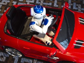 NAO, a humanoid robot, is seen driving a model car during a presentation at an education conference, Thursday, May 3, 2018 in Montreal.