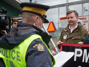 An RCMP officer reads a court order to NDP MP Kennedy Stewart, right, before he was arrested after joining protesters outside Kinder Morgan's facility in Burnaby, B.C., on Friday March 23, 2018.