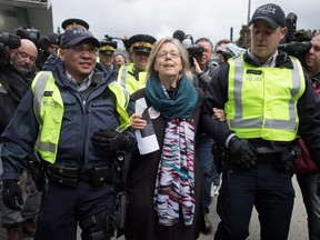 Federal Green Party Leader Elizabeth May, centre, is arrested by RCMP officers after joining protesters outside Kinder Morgan's facility in Burnaby, B.C., on Friday March 23, 2018.