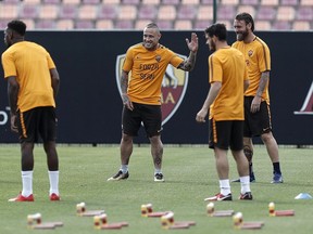 AS Roma's Radja Nainggolan, center, and his teammates wear a shirt with writing reading "Go Sean", dedicated to Liverpool fan Sean Cox, who remains in a medically-induced coma following an assault by Roma fans outside the stadium before the first leg, during their training session, at the Trigoria Sports Center, in Rome, Tuesday, May 1, 2018. AS Roma faces Liverpool in the second leg of the Champions League semifinals on Wednesday.