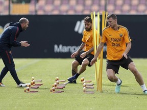 AS Roma's Edin Dzeko, right, and Daniele De Rossi, center, wear shirts with writing reading "Go Sean", dedicated to Liverpool fan Sean Cox, who remains in a medically-induced coma following an assault by Roma fans outside the stadium before the first leg, during their training session, at the Trigoria Sports Center, in Rome, Tuesday, May 1, 2018. AS Roma faces Liverpool in the second leg of the Champions League semifinals on Wednesday.