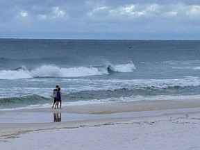 People walk along the beach in Fort Walton Beach, Fla., as a subtropical storm approaches Monday, May 28, 2018. The storm gained the early jump on the 2018 hurricane season as it headed toward anticipated landfall sometime Monday on the northern Gulf Coast, where white sandy beaches emptied of their usual Memorial Day crowds.