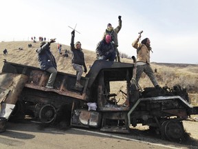 FILE - In this Nov. 21, 2016, file photo, protesters against the Dakota Access oil pipeline stand on a burned-out truck near Cannon Ball, N.D. American Indians' strong support for U.S. Sen. Heidi Heitkamp was a big factor in helping her win a Senate seat in 2012. Six years later, her re-election bid is complicated by fallout from the Dakota Access pipeline issue.