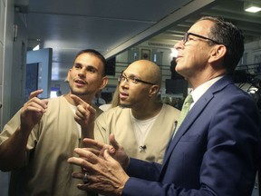Inmates Festim Shyuqeriu, left, and Isschar Howard, middle, tour Connecticut Gov. Dannel P. Malloy around a unit of the Cheshire Correctional Institution in Cheshire, Conn. on Wednesday May 30, 2018. The TRUE Unit is designed to support the needs of 18 to 25 year old inmates, whose brains are still developing.