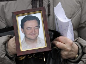 In this Monday, Nov. 30, 2009, file photo a portrait of lawyer Sergei Magnitsky, who died in jail, is held by his mother Nataliya Magnitskaya, as she speaks during an interview with the AP in Moscow.