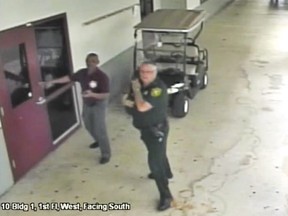A Feb. 14, 2018, frame from security video provided by the Broward County Sheriff's Office shows deputy Scot Peterson, right, outside Marjory Stoneman Douglas High School in Parkland, Fla., as Nikolas Cruz shoots to death 14 students and three staff inside, and wounds 17 others.