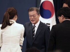 South Korean President Moon Jae-in, center, shakes hands with a journalist afte a press conference at the presidential Blue House in Seoul, South Korea, Sunday, May 27, 2018. Moon said Sunday that North Korean leader Kim Jong Un committed in the rivals' surprise meeting Saturday to sitting down with U.S. President Donald Trump in a summit and to a "complete denuclearization of the Korean Peninsula."