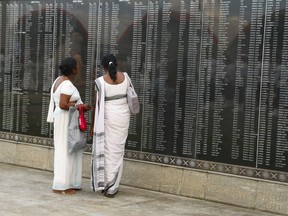 Sri Lanka women read names of fallen soldiers engraved on the national war heroes memorial in Colombo, Sri Lanka, Saturday, May 19, 2018. Sri Lanka's President Maithripala Sirisena on Saturday presided over a state remembrance at a war memorial in capital Colombo where politicians and family members laid wreaths and paid homage to the fallen soldiers.