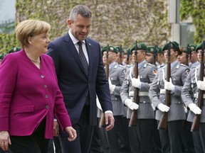 German Chancellor Angela Merkel, left, welcomes the Prime Minsiter of Slovakia, Peter Pellegrini, right, with military honors for a meeting at the chancellery in Berlin, Germany, Wednesday, May 2, 2018.