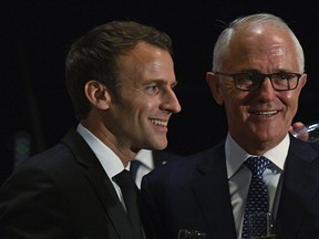 President of France, Emmanuel Macron, left, puts his arm around Australian Prime Minister, Malcolm Turnbull, during a dinner at the Sydney Opera House in Sydney, Tuesday, May 1, 2018.