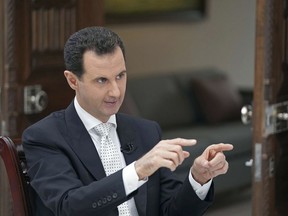 FILE - In this file photo released May 10, 2018, by the Syrian official news agency SANA, Syrian President Bashar Assad speaks during an interview with the Greek Kathimerini newspaper, in Damascus, Syria. In an interview with Russia Today television which aired Thursday, May 31, 2018, Assad said that the U.S. troops, who operate air bases and outposts in the Kurdish-administered region, will have to leave the country. Assad threatened to attack the region held by U.S.-backed Kurdish fighters in northeastern Syria if talks fail to bring the area back under Damascus' authority. (SANA via AP)
