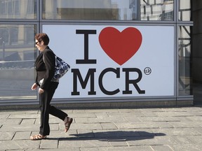 A woman walks past a 'I Love Manchester' sign ahead of the Manchester Arena National Service of Commemoration at Manchester Cathedral to mark one year since the attack on Manchester Arena, Tuesday May 22, 2018.