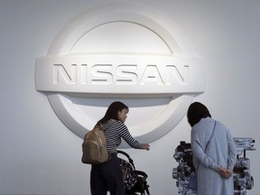 In this Nov. 10, 2017, photo, visitors walk around a gallery of the Nissan Motor Co. at its global headquarters in Yokohama, near Tokyo. Japanese automaker Nissan said Monday, May 14, 2018 its profit fell 32 percent in the last quarter from a year earlier as a strong yen, rising raw materials costs and research expenses bit into earnings.