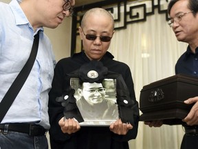 In this July 15, 2017, file photo provided by the Shenyang Municipal Information Office, Liu Xia, center, wife of jailed Nobel Peace Prize winner and Chinese dissident Liu Xiaobo, holds a portrait of him during his funeral at a funeral parlor in Shenyang in northeastern China's Liaoning Province. A close friend of the late Chinese Nobel Peace laureate Liu Xiaobo has released a recording of an emotional phone call with his widow. Liu Xia has never been charged with a crime, but has been kept guarded and largely isolated since her late husband was awarded the Nobel Peace Prize for his human rights activism in 2010. He was still serving a prison sentence for "subversion" when he died last summer.  (Shenyang Municipal Information Office via AP, File)