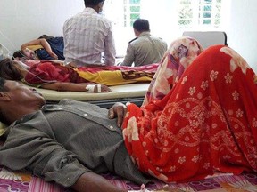 In this Sunday, May 6, 2018, photo provided by Cambodia National Police, patients, who sickened from drinking water, lie on beds at a hospital in Kratie province in northeast of Phnom Penh, Cambodia. A senior Cambodian health official said Monday, May 7, 2018, 14 villagers whose sudden deaths were thought to have been caused by polluted water actually died from drinking rice wine containing methanol. (Cambodia National Police via AP)